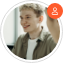 A circular profile picture of a smiling young man with light blonde hair