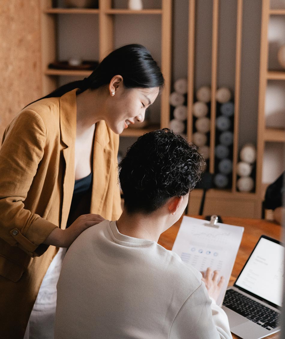 Two people collaborating over a laptop and documents.